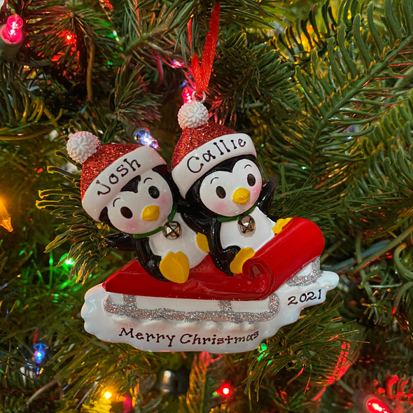 Pinguinpaar auf rotem Schlitten, personalisierter Weihnachtsschmuck aus dem Jahr 1915-2
