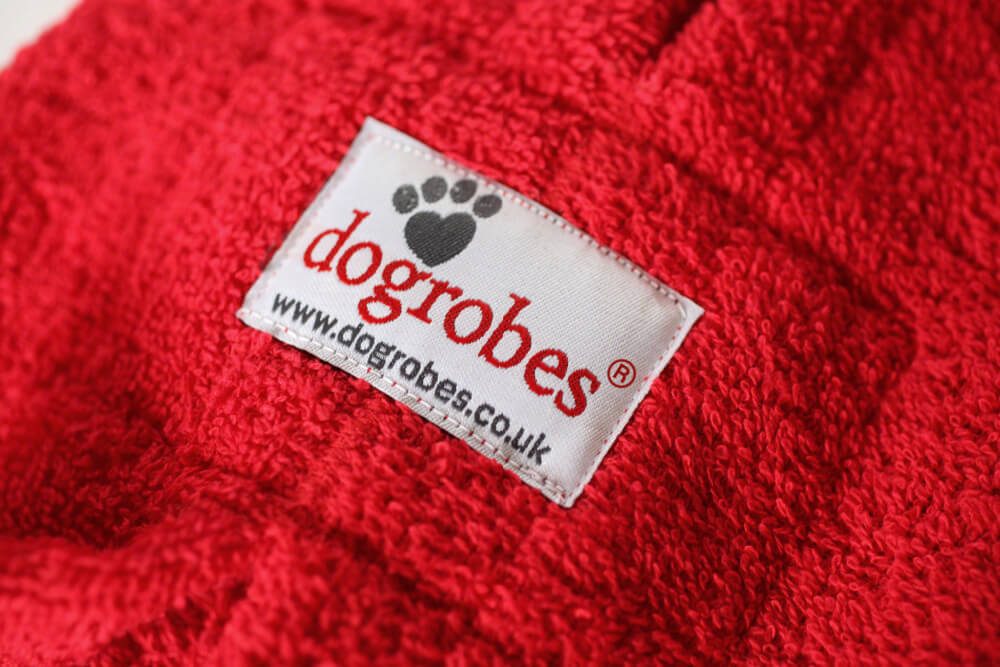 Close-up of Dogrobes fabric label showing premium red cotton towelling and quality craftsmanship