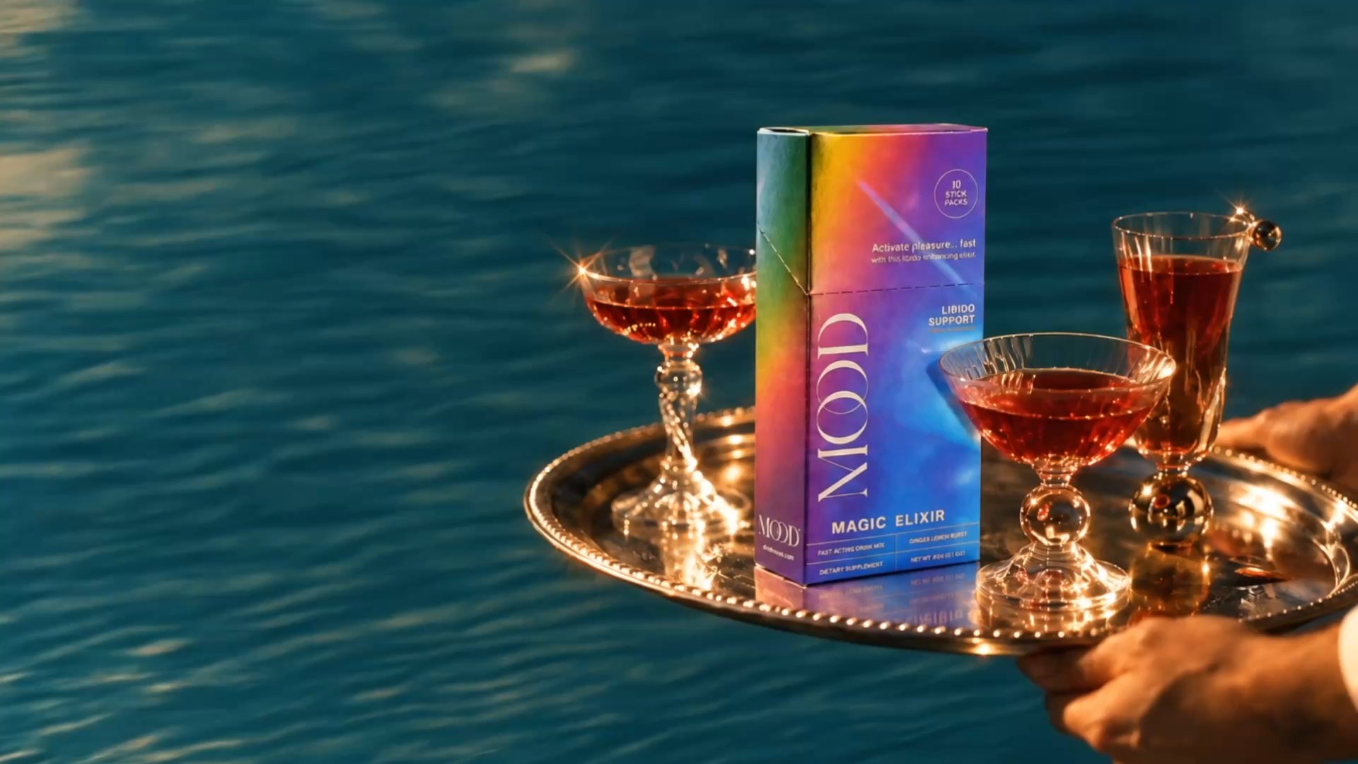 MOOD box and ruby drinks beside sunlit teal water