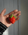 A handmade crochet strawberry keychain in red