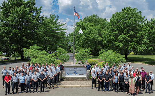 all KOMO and PMC group employees outside in front of the building sign.
