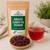 Organic Hibiscus Flower Tea (Premium) in The Tea Hut certified organic kraft pouch, with loose premium hibiscus flowers beside a bright ruby-red brewed cup.