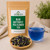 Bulk Blue Butterfly Pea Flower Tea in The Tea Hut kraft pouch, with loose whole blue butterfly pea flowers beside a vivid royal-blue brewed cup.