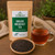 Organic English Breakfast Tea in The Tea Hut certified organic kraft pouch, with loose black tea leaves beside a deep amber brewed cup.