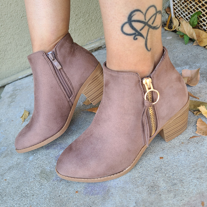 A pair of stylish Taupe Suede ankle boots with a modern design, featuring side zippers adorned with a circular zipper pull  and chunky wooden heels for a comfortable yet fashionable look