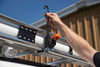 Prime Design ACC-8000 Retractable Ratchet Tie-Down, orange and black, secured to metal rail.