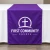 Purple custom printed table runner with church cross logo over a white tablecloth
