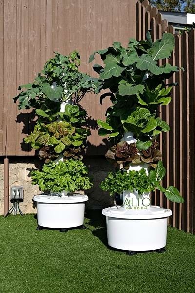 A tall, cylindrical hydroponic tower system with lush green plants.
