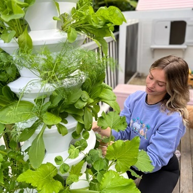 woman attending to her hydroponic tower on her balcony