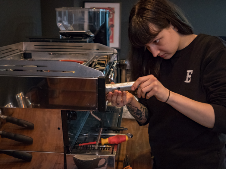 Extract Coffee Roasters Espresso Machine Technician Job Role - Female Tech repairing espresso machine