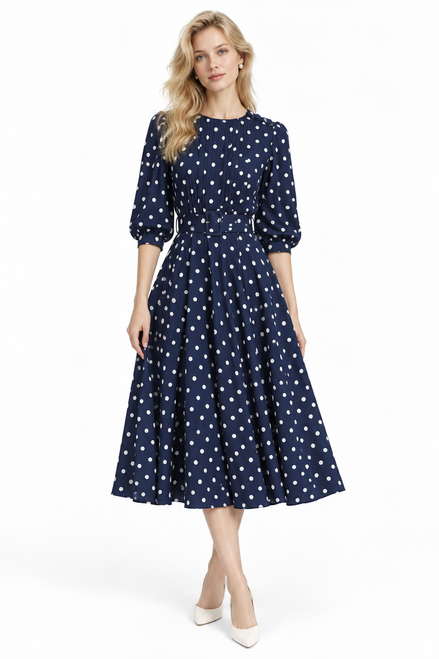 Model wearing a navy polka dot pleated midi dress with a buckle belt