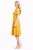 Model wearing a ginger yellow pleated midi dress with puff sleeves, a notched neckline and matching belt