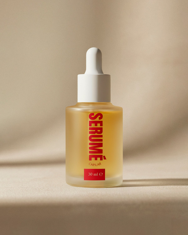 Botella de vidrio del serum capilar hidratante marca Serumé sobre fondo rojo, tratamiento para el crecimiento y brillo.