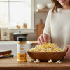 Amish Country cheddar cheese popcorn seasoning bottle beside bowl of cheesy popcorn on kitchen counter