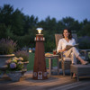 Solar-powered cedar lighthouse garden statue lighting a backyard patio at dusk.