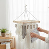 Small wooden clothespin hanger rack holding baby clothes and socks by a bright window
