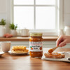 Sweet Potato Butter being spread on toast beside a jar of The Dutch Kettle No Granulated Sugar Added Sweet Potato Butter in a bright kitchen setting.
