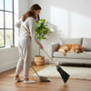 Woman sweeping hardwood floor with an Amish-made natural broom while a golden retriever rests on the couch