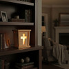Light up Cross Wooden Lantern placed on a bookshelf in a den as a nighttime nightlight in a cozy home. Order today at harvestarray.com.