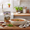 A 4oz. package of Evelyn's Elegant Edibles Red Beans and Rice Soup Mix next to a bowl of Red Beans & Rice Soup in a bright Kitchen.