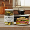 A jar of Annie's Kitchen Sweet Seven Day Pickles  next to a sandwich on a plate on a table in a rustic country kitchen.