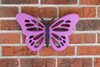 Purple poly butterfly decoration displayed on a brick wall