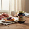Black raspberry seedless jam being spread on toast next to a jar of The Dutch Kettle Black Raspberry Jam on a rustic breakfast table.