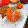Top down view of Orange Yarn Pumpkin with Raffia tied around wooden stem and wire curl.
