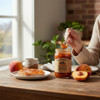 Peach butter spread on toast with The Dutch Kettle Peach Butter jar on a rustic kitchen table