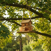 Handcrafted wooden Noah’s Ark birdhouse hanging from a tree branch in a garden