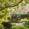 Green Amish-made log cabin birdhouse hanging from a tree branch with birds feeding in a garden