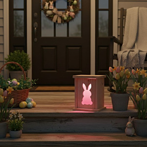 A rustic front porch decorated with spring flowers for Easter on a spring night. The steps are illuminated by a Pink Rabbit Wooden Handcrafted LED Lantern. Order online from Harvest Array.