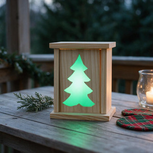 Christmas Tree Rustic Wood LED Lantern sitting on an outdoor porch table as a holiday decoration. It's lit up at night.