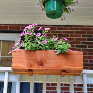 Harvest Array's Exclusive Cedar Planter from M&M Enterprises with flowers in it and set on a porch railing. Update your railing with a cedar planter only from harvestarray.com.