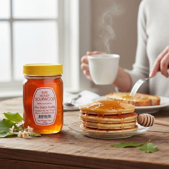 Pure sourwood honey jar with pancakes drizzled in honey on a wooden breakfast table