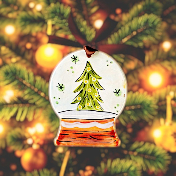 Hand-painted snow globe ornament with a Christmas tree inside, topped with a silver ribbon.
