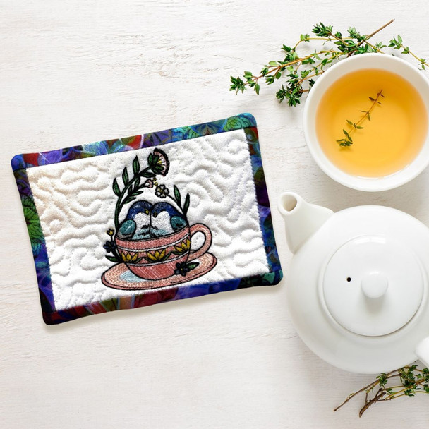 Cute little love birds snuggling in a teacup are featured in our Mug Rug.  Order yours today at harvestarray.com.