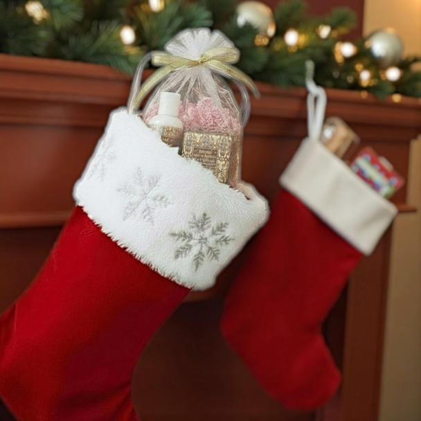 Red Christmas stocking with Almond Cocoa Butter Soap and Lotion Gift Bag inside, hanging by a fireplace with Christmas decorations.
