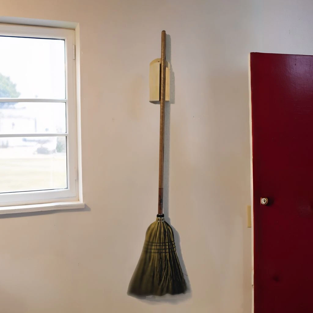 Plain wood Amish-made broom holder mounted to a kitchen wall