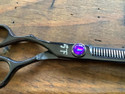 Shear Fanatic™️ Scissor Shear Fanatic®️ Pro Series Black Left Hand 35 Tooth Texturizing Shears, professional black scissors with a purple decorative screw, on a wooden surface.