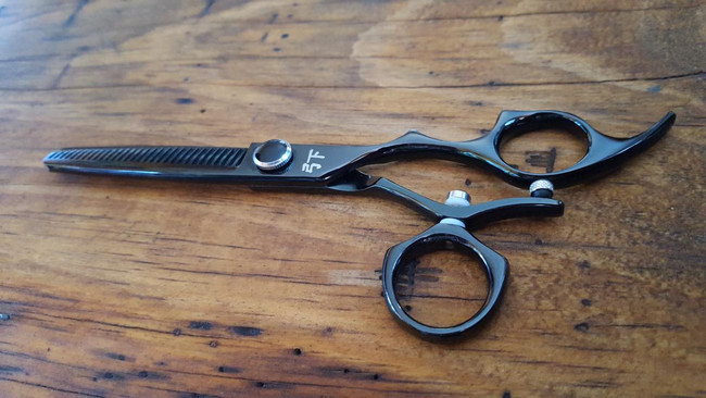 Shear Fanatic™️ Scissor Shear Fanatic®️ Craft Series Twister Black Single or Double Swivel 35 Tooth Thinning Shear 6.0", professional Japanese 440C stainless steel thinning shear with black finish, featuring a twisting design and adjustable swivel finger rests on a wooden surface.