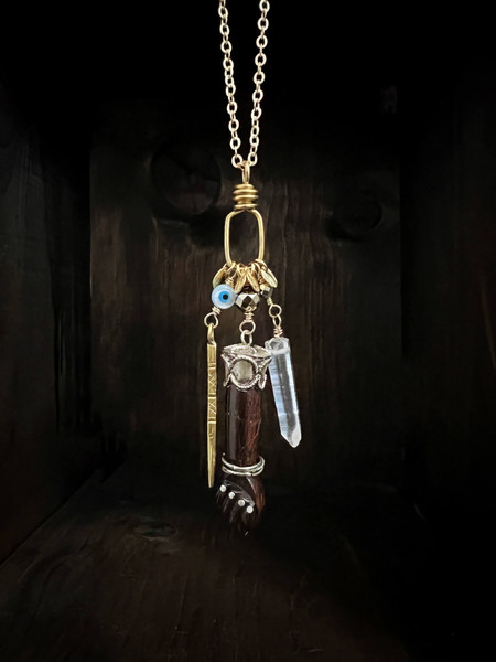 Antique carved wooden Mano Figa with silver inlay and accents with pyrite, etched brass spike and MOP evil eye, Quartz point and brass discs hanging on a 32” long brass chain with 24K Russian gold filled lobster clasp.