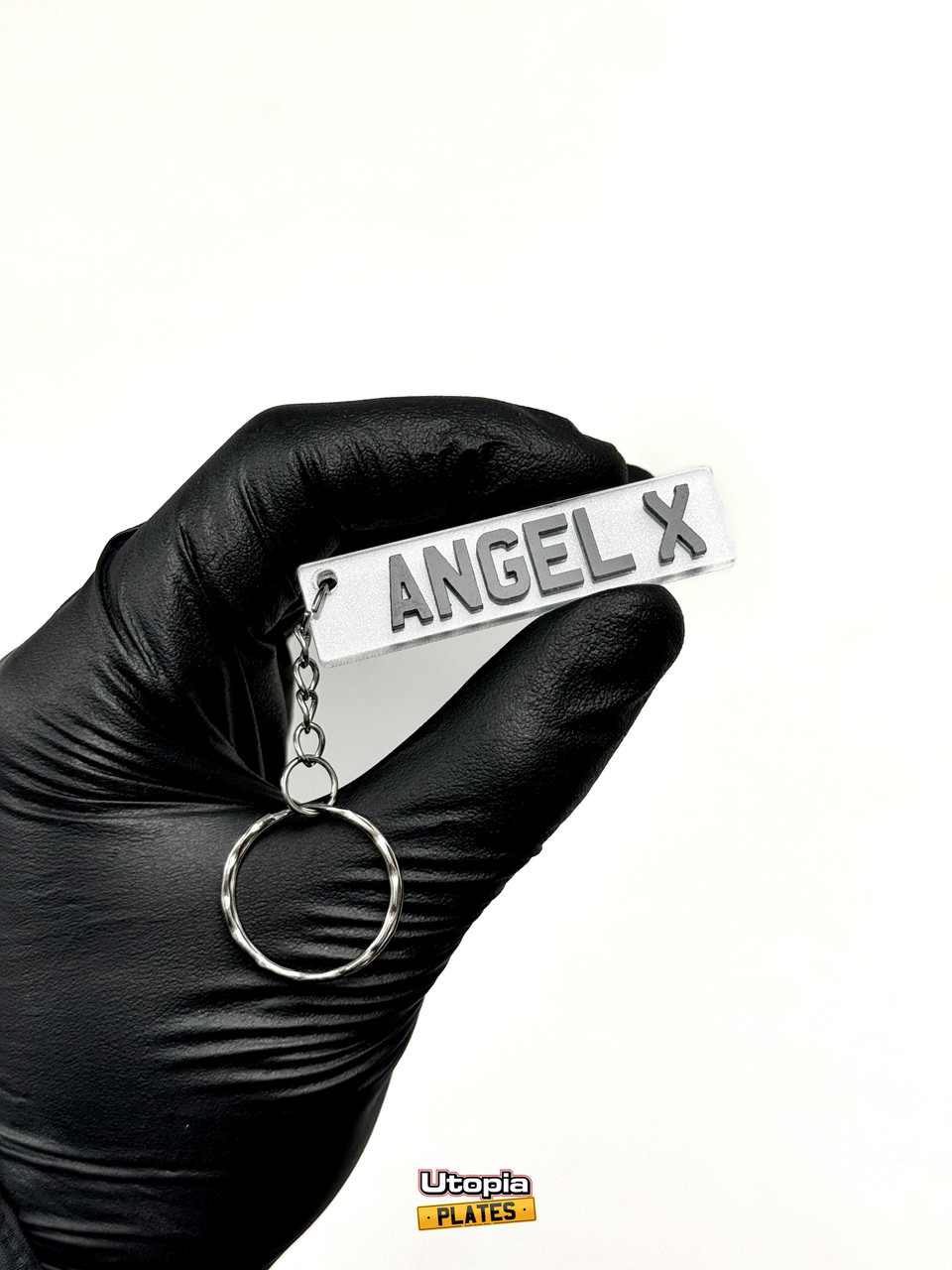 A white 4D style front number plate keyring featuring the text "ANGEL X"