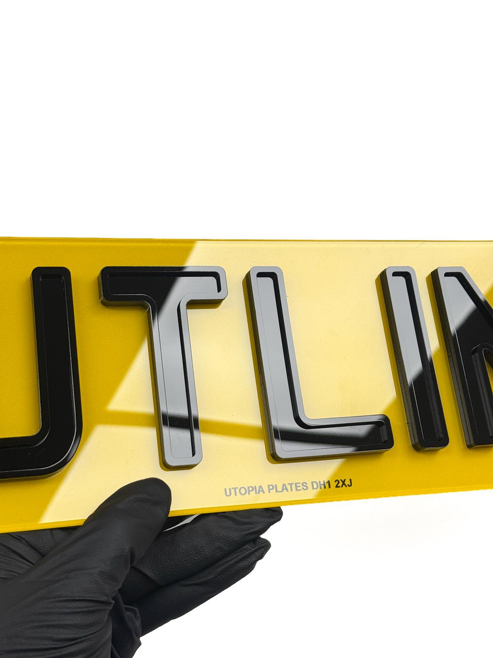 Close-up of Outline 4D plate characters showing the 3mm black acrylic base layer and bonded outline layer in Charles Wright font