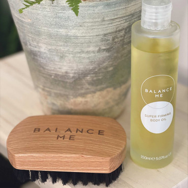 Balance Me body brush and oil in a bathroom.