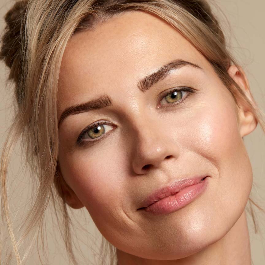 Dirty blond haired woman smiliing with Seint makeup.