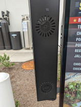 Close-up of a black menu-mounted speaker-mic housing attached to a drive-thru menu display.