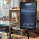 A vertical digital menu board displaying cafe food items, prices, and calorie counts for Pure Eats.