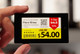 A hand holding a smart shelf label showing a discounted Cabernet Sauvignon price with a QR code.