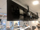 An angled rear-view perspective of a multi-screen commercial menu board system, demonstrating the hardware mounting and cabling infrastructure that allows for a stable, zero-gap installation in high-traffic areas.